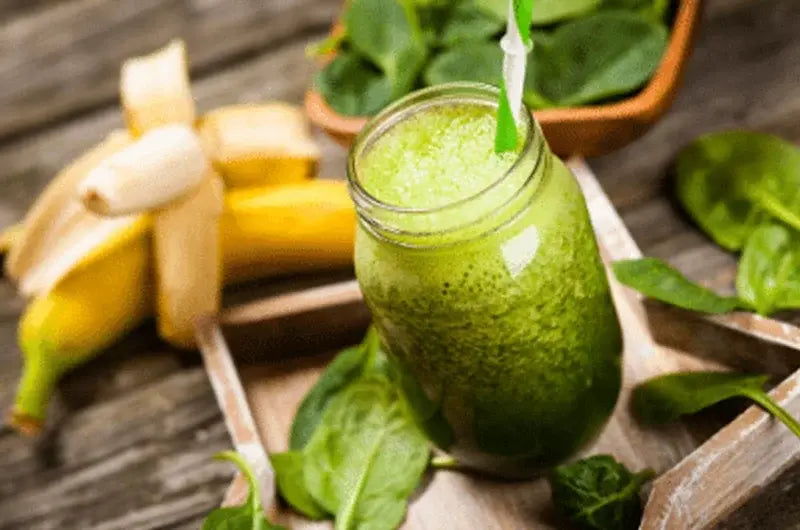 Two glasses of simple green smoothie made with banana, strawberry, spinach and coconut milk