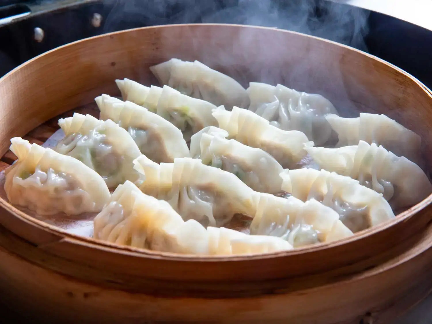 Steamed pork dumplings on a plate with dipping sauce
