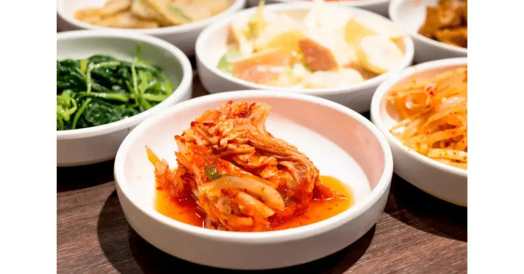 An assortment of Korean side dishes including kimchi, bean sprouts, and pickled vegetables