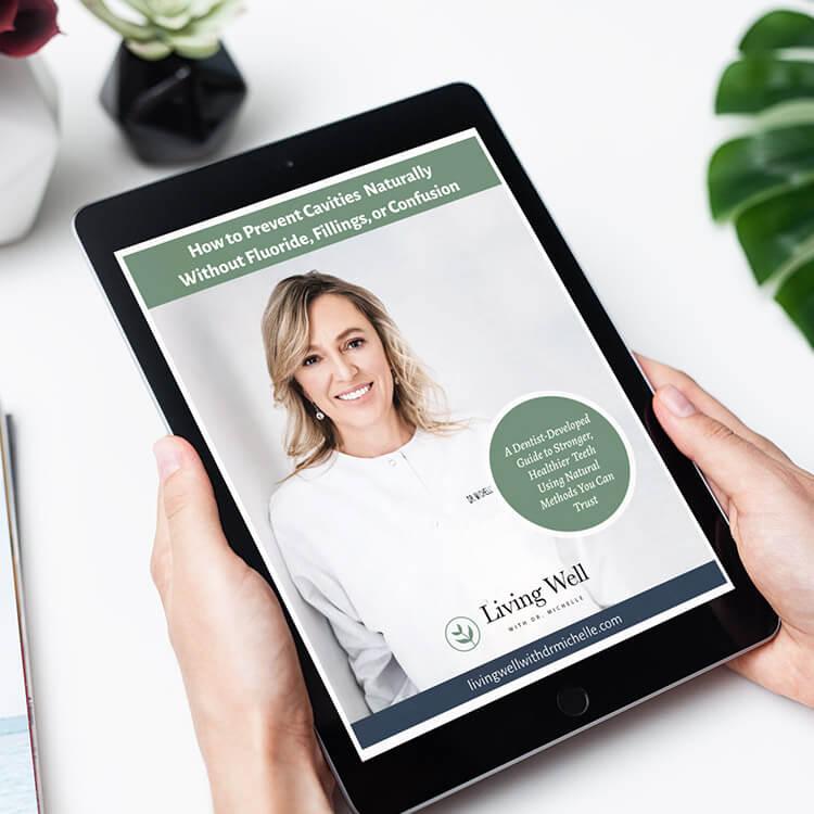 How to Prevent Cavities Naturally, the free guide by Dr. Michelle, held on a tablet